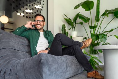 Ofisteki koltukta müşteriyle konuşan kendine güvenen işadamının düşük açılı görüntüsü