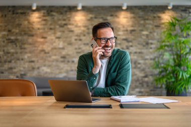 Cep telefonuyla iletişim kuran gözlüklü mutlu mali danışman.