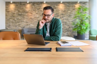 Modern ofiste masa başında bilgisayar yazılımı geliştiren kendine güvenen web tasarımcısının portresi