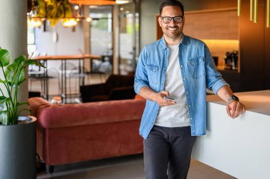 Makamdayken akıllı telefondan gülümseyen ve mesaj atan kendinden emin erkek mühendisin portresi