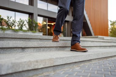 Üst düzey işadamlarının kahverengi deri ayakkabılar giyip modern şehirde merdivenlerden aşağı inen alt kesimi.