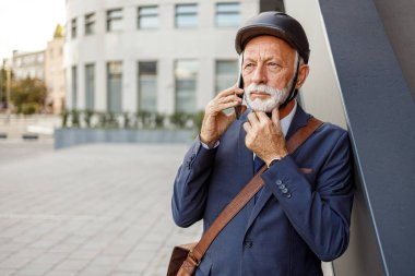 Kasklı, ciddi bir girişimcinin portresi şehrin duvarında dururken telefon görüşmesini dinliyor.