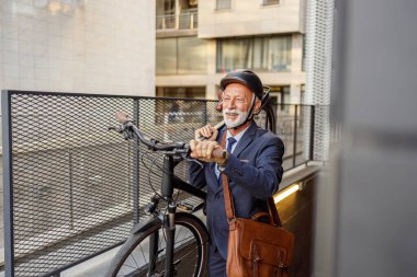Kendinden emin kıdemli işadamı metroda hareket ederken sırıtıyor ve omzunda bisiklet taşıyor.