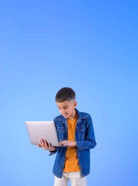 İzole edilmiş mavi arka planda dururken internette çalışan genç yöneticinin portresi