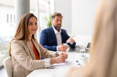 Toplantıda erkek meslektaşımla gülümseyen kadın avukat toplantı odasında yasal belgeleri tartışıyor ve gözden geçiriyorlar.