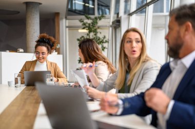 Bir grup profesyonel girişimci toplantı odasında birlikte otururken stratejileri tartışıyorlar.