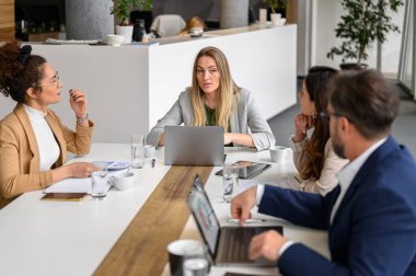 Kurul odasında birlikte çalışırken beyin fırtınası yapan ve sorunları çözen bir grup kendine güvenen girişimci
