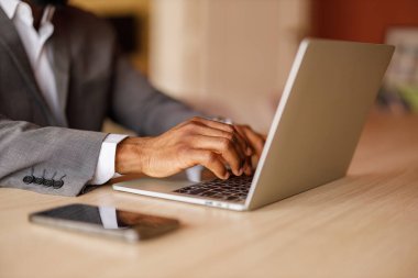 Şirket ofisindeki masadaki dizüstü bilgisayarda e-posta yazan erkek girişimcilerin elleri.