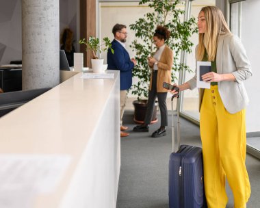 Bavulu ve pasaportu olan sarışın kadın bir iş gezisi sırasında otel resepsiyonuna giriş yapmış.