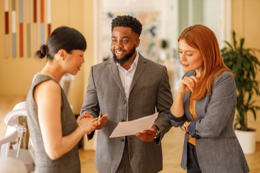 Ofisteki takım tartışması sırasında kadın meslektaşlarıyla finansal belgeleri analiz eden güvenilir bir işadamı.