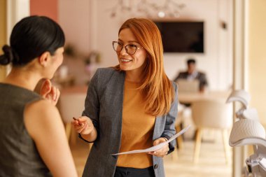 Belgeleri inceleyen ve ofiste birlikte çalışırken fikir ve stratejileri paylaşan kadın profesyoneller