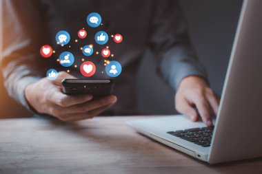 Sosyal medya simgesi gibi mavi ve kırmızı kalpli akıllı telefondan sohbet ve bilgilendirme. Tatilde akıllı telefonu hologramla kullanan adam. Sosyal medya ve dijital çevrimiçi kavram.