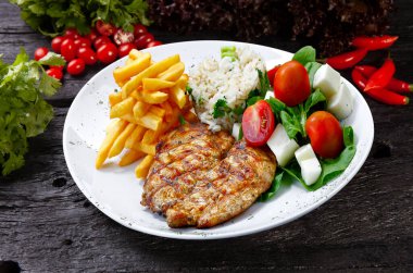 Kızarmış tavuk bifteği, patates, pilav ve salata. 