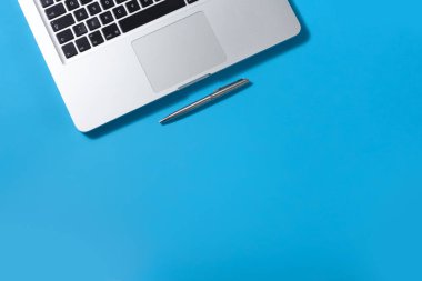 Ofis masasında beyaz dizüstü bilgisayar, defter, masa üzerinde kalem. Çalışma alanı. Metin için boş alanı olan tablonun üst görünümü. Şimdi düzenle