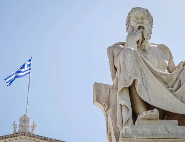 Socrates marble statue and the Greek flag under clear bue sky, Athens Greece