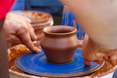Yakushyntsi, Ukrayna - 24.07.2021: Geleneksel çömlekçilik çarkında bir çömlekçi el oluşturma, etnografi dersi geleneksel ekolojik mutfak ürünleri yapımı, hareket bulanıklığı etkisi