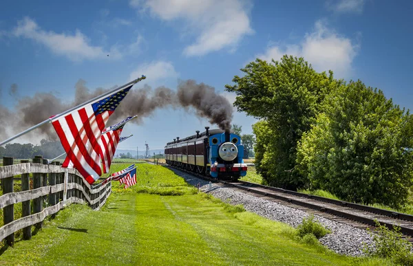 Strasburg, Pennsylvania. 48 Haziran 2021 - Güneşli bir günde Çit Üzerinde Amerikan Bayraklarını Geçerken Yolcu Arabalarını Çeken Thomas