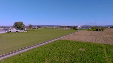 An Aerial View of a Single Rail Road Track Going Thru Country Farmlands as a Steam Train Approaches in the Distance on a Sunny Fall