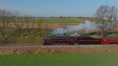 Ronks, Pennsylvania, November 9, 2022 - Drone Traveling Parallel View of a Steam Passenger Train Blowing Lots of Smoke and Steam on a Sunny Fall Day