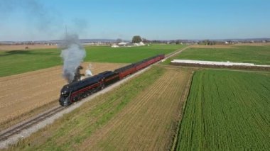 Ronks, Pennsylvania, November 9, 2022 - Drone View of a Steam Passenger Train Blowing Lots of Smoke and Steam Traveling Slowly on a Sunny Fall Day