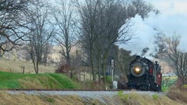 Ronks, Pennsylvania, November 13, 2022 - A View of a Steam Passenger Train Approaching From a Long Distance on a Cold Fall Day With Lots of Smoke