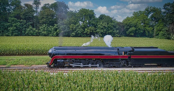Drone View of an Antique Steam Engine, Approaching, Blowing Steam and Traveling Along the Countryside on a Sunny Day