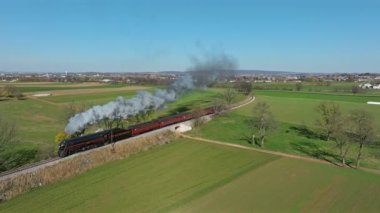 Ronks, Pennsylvania, November 9, 2022 - Drone Traveling Ahead of View of a Steam Passenger Train Blowing Lots of Smoke and Steam on a Sunny Fall Day