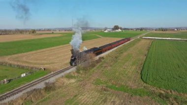 Ronks, Pennsylvania, November 9, 2022 - Drone View of a Steam Passenger Train Blowing Lots of Smoke and Steam Traveling Slowly on a Sunny Fall Day
