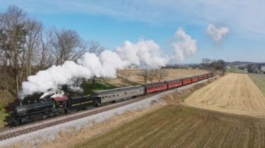 Ronks, Pennsylvania, December 4, 2022 - An Aerial View of a Steam Passenger Train Approaching Along, Traveling Thru the Farmlands, on a Sunny Winter Day
