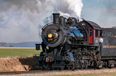 Ronks, Pennsylvania, December 28, 2022 - A View of a Classic Steam Passenger Train Approaching, Traveling Thru the Countryside, Blowing Smoke and Steam on a Winter Day