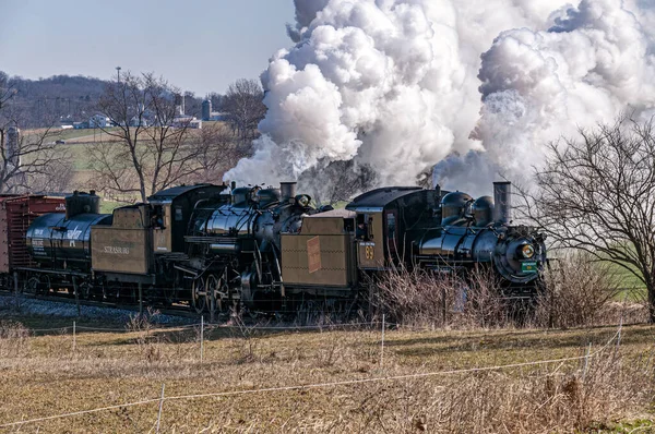 stock image Ronks, Pennsylvania, February 18, 2023 - A View of a Steam Double Header Freight Train Traveling Thru Rural America Blowing Lots of Smoke and Steam on a Sunny Winter Day