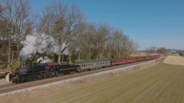 2022年2月1日ペンシルベニア州ロンクス 晴れた冬の日に煙を吹く小さな駅を通過する復元された蒸気旅客列車の側面の眺め — ストック動画
