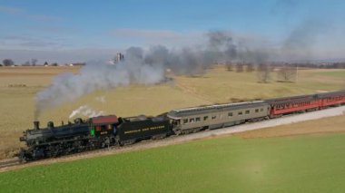 Ronks, Pennsylvania, 30 Aralık 2022 - Güneşli bir kış gününde, Güneşli bir kış gününde, Thru the Country 'yi gezerken, Buharlı Yolcu Treni' nin Yavaş Çekimde Görünüşü, Yaklaşan, Dumanı Tüten Trenin Yankısı