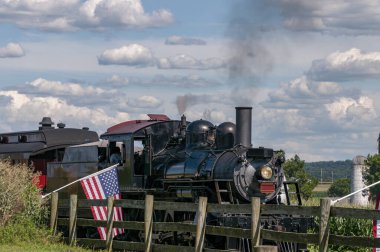 Yenilenmiş Antika Buharlı Yolcu Treni, güneşli bir yaz gününde nazikçe Amerikan bayraklarını sallayarak bir çatışmaya giriyor.