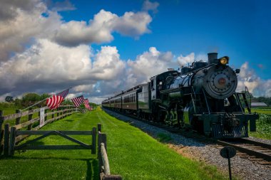 Ronks, Pennsylvania, 19 Temmuz 2022 - Güneşli bir yaz gününde restore edilmiş Antika Buharlı Yolcu Treni Nazikçe Amerikan Bayraklarını sallayarak Çite Yaklaştı