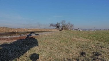 Ronks, Pennsylvania, 30 Aralık 2022 - Güneşli bir kış gününde Buharlı Yolcu Treni 'nin Düşük Açısı Yaklaşmakta ve Geçmekte Olan Dumanı