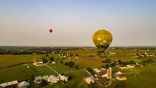 トウモロコシや他の野菜や家の農場フィールドに浮かぶ複数のカラフルな熱気球の空中ビューは 晴れた夏の朝に — ストック写真