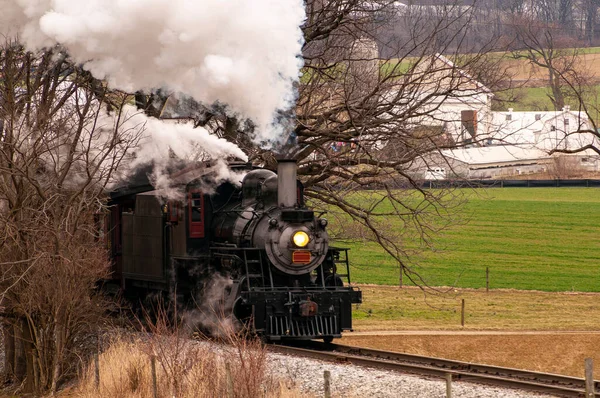 在冬日 一列还原蒸汽客运列车驶出一片树林 喷出浓烟和蒸汽的景象 — 图库照片