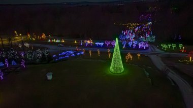 Açık Çayırlar ve Açık Bir Gece Binası 'ndaki Renkli Işıklar, Ağaçlar ve Manzaralarla Büyük Sürücü Noel Gösterimi' nin Drone görüntüsü