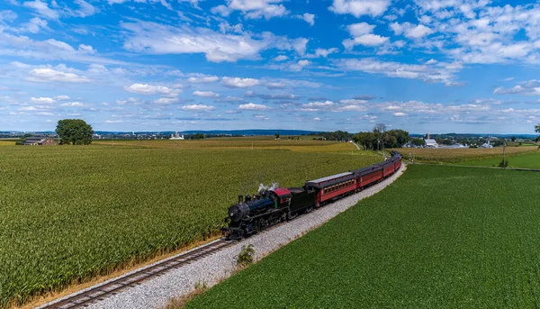 stock image A Drone Frontal View of a Restored Steam Passenger Train, Traveling Thru Green Corn Fields, Blowing Smoke on a Fall Day