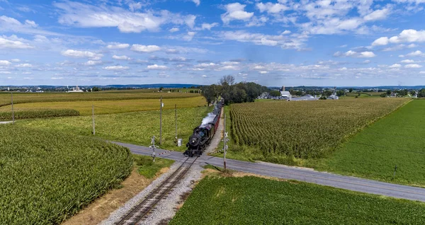 Stock image A Drone Frontal View of a Restored Steam Passenger Train, Traveling Thru Green Corn Fields, Blowing Smoke on a Fall Day