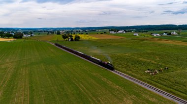 Antika Buharlı Yolcu Treni Thru Çiftlikleri 'ni geziyor, ekili ekinler, güneşli bir bahar gününde duman üflüyor.