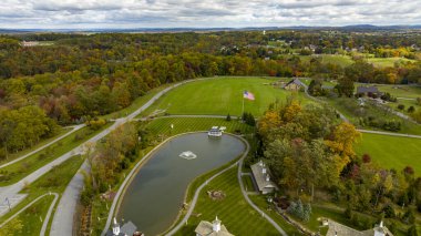 Güneşli bir sonbahar gününde Gölet ve Amerikan Bayrağıyla Sonbahar ve Güneş Kırsalının Havadan Görünümü