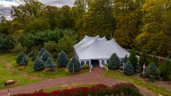 An Aerial View of a Large Tent in the Middle of all Kinds of Trees in Autumn