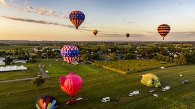 Güneşli bir yaz sabahı, Pensilvanya 'nın kırsal kesimlerinde, birden fazla sıcak hava balonunun fırlatılması ve sürüklenmesinin hava görüntüsü.