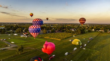 Güneşli bir yaz sabahı, Pensilvanya 'nın kırsal kesimlerinde, birden fazla sıcak hava balonunun fırlatılması ve sürüklenmesinin hava görüntüsü.