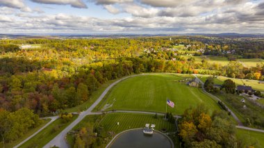Güneşli bir sonbahar gününde Gölet ve Amerikan Bayrağıyla Sonbahar ve Güneş Kırsalının Havadan Görünümü