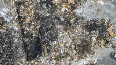 Yoldaki arabalarla ve bulutlu bir gökyüzünün altındaki yeşil alanlarla çevrili yıkık dökük bir binanın hava görüntüsü..