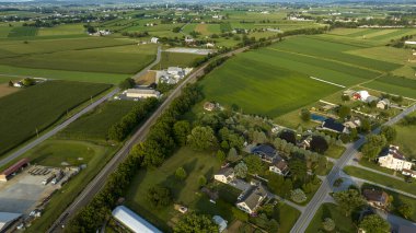 Bereketli tarlaları olan huzurlu bir kırsal alan, yola paralel bir demiryolu ve ekin tarlalarının kenarındaki ağaçların arasına yerleştirilmiş evler..