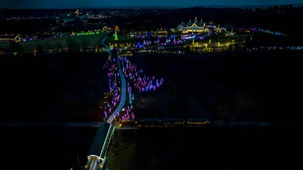 照らされた複合体および反射水ボディに伸びるお祝いのライトと装飾される夜間道路の航空展望 — ストック写真